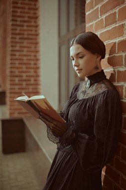 Güzel, sofistike bir kızın portresi. Katı siyah elbiseli, sırtı siyah, bir binanın yanında duran ve kitap okuyan. 19. yüzyılın romanının kahramanı.. 