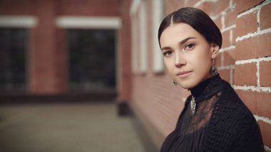 Katı siyah elbiseli, sırtı siyah saçları çekilmiş, sokakta duvara yaslanmış hoş, sofistike bir bayan. 19. yüzyılın romanının kahramanı. Boşluğu kopyala.