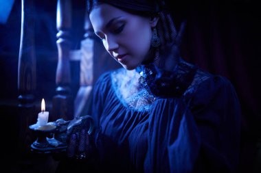 Siyah elbiseli güzel bir aristokrat kız elinde mumla merdivenin yanında duruyor ve bir gece evindeki sesleri dinliyor. Mistik bir atmosfer. Romandaki kadın kahraman..