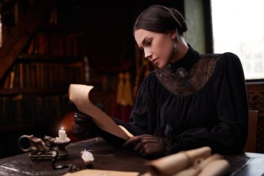 Romanın kahramanı, 19. yüzyıl tarzı. Siyah zarif elbiseli, koyu renk saçlı sevimli aristokrat kız eski bir odada oturmuş bir mektup okuyor.. 