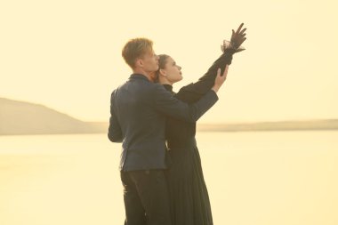 Yakışıklı genç bir adam ve siyah şık elbiseli güzel bir kadın deniz kenarında birbirlerine yakın durup gökyüzünü işaret ederek hayal kuruyorlar. Tarihi aşk romanı. 19. yüzyıl.