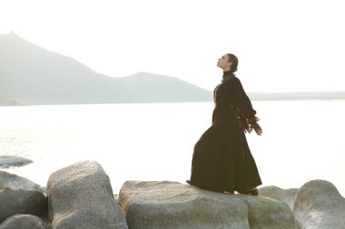 Siyah zarif elbiseli zarif bir bayan, ne yazık ki deniz kenarında duygularından muzdarip duruyor. 19. yüzyıl romanı. Boşluğu kopyala.