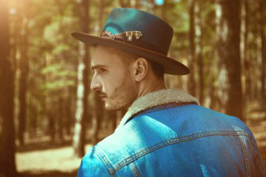 Yakışıklı bir turist çam ormanında yürüyor. Hipster açık havada. Yürüyüş, seyahat ve turizm.