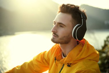 Erkek bir turist gün batımıyla tanışır ve güzel bir manzaraya karşı bir dağda oturup kulaklıkla hoş müzikler dinler. Seyahat, yaz tatilleri. Doğayla uyum..