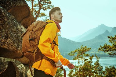 Sırt çantasıyla dağlarda gezen genç bir turistin portresi. Güzel dağların manzarası. Turizm, yürüyüş. Yaz tatili.