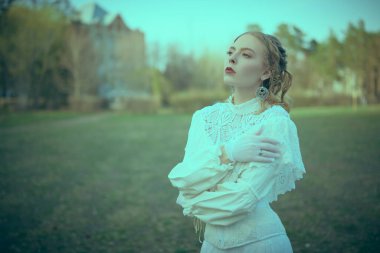 Beyaz dantel elbiseli zarif, güzel bir aristokrat kız sarayın parkında hayaller içinde duruyor. Viktorya tarzı. Tarihi roman..