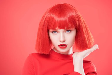 Parlak kırmızı dudaklı ve kızıl saçlı sevimli bir kız. Kırmızı stüdyo geçmişi. Güzellik, makyaj. Saç stili, saç boyası. Modaya uygun kırmızı renk.