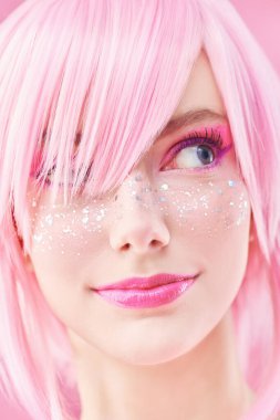 Pembe saçlı, parlak pembe makyajlı ve parlak çilli güzel bir kızın yakın plan portresi. Asya anime tarzı. Saç stili, kozmetik ve makyaj.