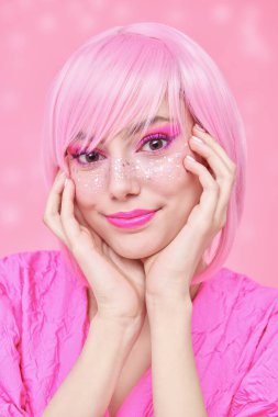 Pembe kız tarzı. Pembe saçlı, pembe makyajlı ve parlak çilli güzel bir genç kızın portresi. Asya anime tarzı. Pembe arkaplan.