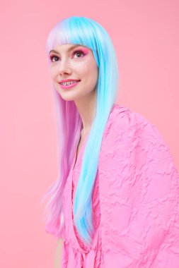 Japon animasyon tarzı. Parlak makyajlı, menekşe mavisi peruklu, şık pembe elbiseli güzel bir kız. Pembe arka planda stüdyo portresi. Moda. Saç stili, saç rengi, makyaj..