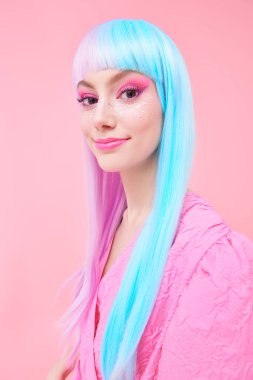 Parlak makyajlı, menekşe mavisi peruklu ve pembe elbisesi olan sevimli bir kız pembe arka planda poz veriyor. Moda. Saç stili, saç boyası, makyaj. Japon animasyon tarzı. 