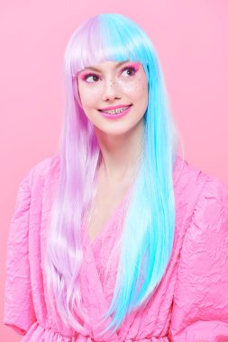 Japon animasyon tarzı. Parlak makyajlı, menekşe mavisi peruklu, şık pembe elbiseli güzel bir kız. Pembe arka planda stüdyo portresi. Moda. Saç stili, saç rengi, makyaj..