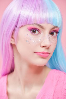 Yumuşak, güzel bir kız mor-mavi saçlı ve parlak parlak parlak çilli pembe makyajlı. Pembe arka planda stüdyo portresi. Saç stili, saç boyası. Makyaj ve kozmetik.