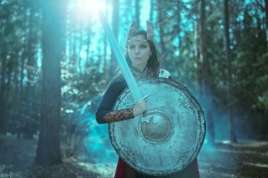 Kılıcı ve kalkanı olan cesur savaşçı Valkyrie 'nin portresi ormanda tetikte bekliyor. İskandinav mitolojisi. Efsanevi fantezi. 
