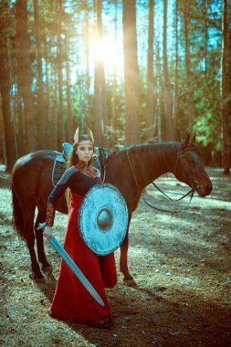 Kılıcı ve kalkanı olan cesur savaşçı Valkyrie 'nin portresi ormanda tetikte bekliyor. İskandinav mitolojisi. Efsanevi fantezi. 