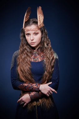 Mavi arka planda duran güzel bir Valkyrie kadını. İskandinav mitolojisi. Fantezi.