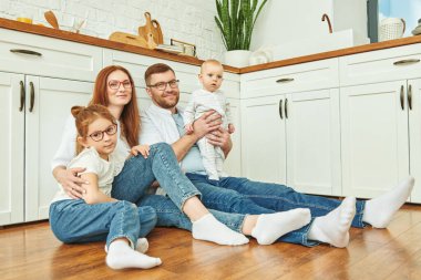 - Aile. Mutfakta yerde neşeyle oturan mutlu aile portresi. Modern iç mekan, mutfak mobilyası.. 