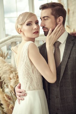Güzel, zarif gelin ve lüks gelinlik içinde yakışıklı damat nazikçe sarılıyorlar. Gelin ve damat. Düğün modası. Lüks stil.