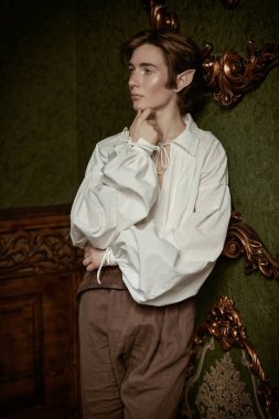 Yakışıklı bir elf çocuğu düşünceli bir şekilde sihirli kalesinde duruyor. Fantezi. Peri masalı, sihir. 