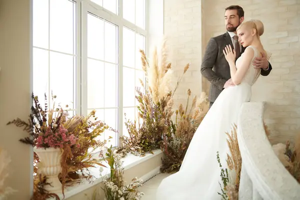 stock image Handsome, elegant groom hugging his beloved bride in luxury white dress. Full-length portrait. Wedding fashion.