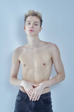 Erkek sağlığı. Siyah kotlu, ince gövdeli, sağlıksız ve zayıf görünen genç bir adamın portresi. Beyaz arka plan. Stüdyo çekimi.