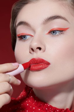 Güzellik kızı. Sevimli kırmızı renk. Parlak makyajlı güzel bir kız modelin portresi. Muhteşem bir kırmızı ruj sürüyor. Yakın çekim..