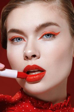 Güzellik kızı. Sevimli kırmızı renk. Parlak makyajlı güzel bir kız modelin portresi. Muhteşem bir kırmızı ruj sürüyor. Yakın çekim..