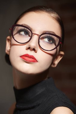 Parlak makyajlı, şık gözlükleri olan, siyah örülü bir beden giysisi giyen zarif bir kız. Moda fotoğrafı. Makyaj ve gözlük stili.