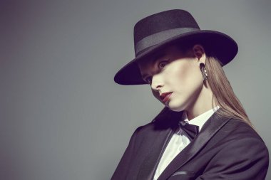 Zarif, sıkı siyah bir takım elbise giymiş, papyon takmış ve gözlerini kapatmış bir kadın modelin portresi. Mükemmel iş görünüşü. Moda fotoğrafı.. 