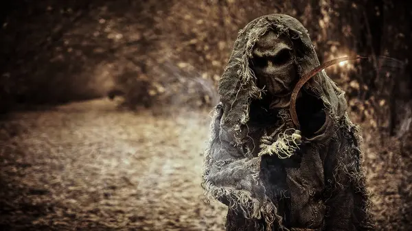 stock image Halloween Tales. Horror, thriller. A portrait of an evil Scarecrow with a canvas bag on his head and in a burlap robe, standing in a deep forest on a sunset. Vintage style. Copy space.