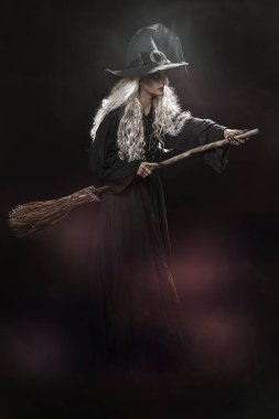 Cadılar Bayramı. Siyah bir arka planda sihirli süpürgesiyle duran çirkin yaşlı bir cadının tam boy portresi. Büyücülük..