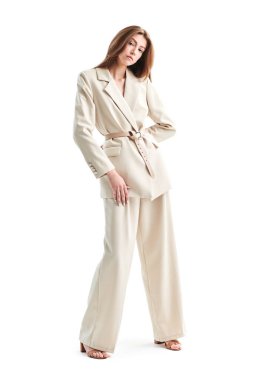 Beyaz bir stüdyo arka planında bol bej bir takım elbise giymiş güzel kahverengi saçlı bir mankenin tam boy çekimi. Zarif bir tarz. Moda fotoğrafı.. 