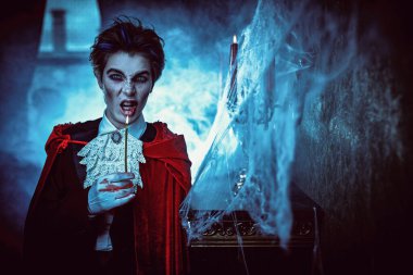 Vampirler. Terk edilmiş bir ortaçağ şatosunda elinde mumla durup şeytanca sırıtan genç bir vampir aristokratı. Vampirler hakkında bir roman. Cadılar Bayramı. Boşluğu kopyala.