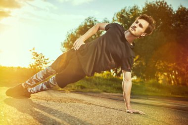 Aktif bir genç adam gün batımında parkta antrenman yapıyor. Spor ve spor. Etkin yaşam biçimi.