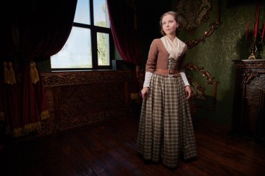 18. yüzyıldan kalma İskoç elbiseli hoş bir aristokrat kız klasik iç mimarisi olan bir odada duruyor. Romanın kadın kahramanı. 18. yüzyıl tarzı. Boşluğu kopyala.