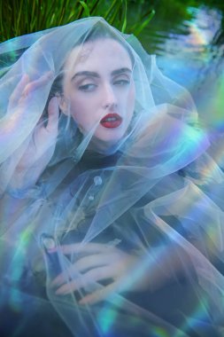 Büyüleyici bir su perisi duvakla kaplı bir şekilde nehrin suyunda yatıyor. Fantezi. Peri masalları ve efsaneler. 