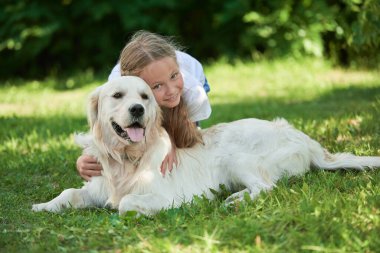 Bir yaz parkında yeşil çimlerin üzerinde köpeğiyle oynayan mutlu bir kızın portresi. Yaz tatili. Parkta dinlen..