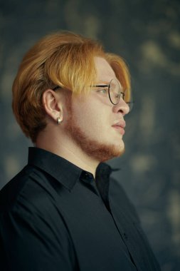 Siyah tişörtlü, siyah gözlüklü, şişman, genç bir adamın portresi dalgın dalgın bakıyor. Stüdyo çekimi. Modern genç adam..