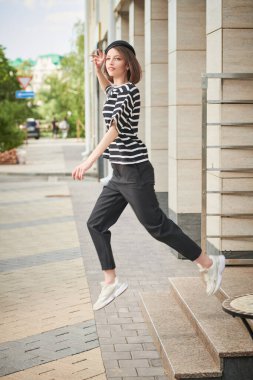 Yaz havası, tatil. Kısa saçlı, çizgili bluz giymiş ve siyah pantolonlu, tasasız, hoş bir kız şehir caddesinde neşeyle zıplıyor. Yaz kadın modası.