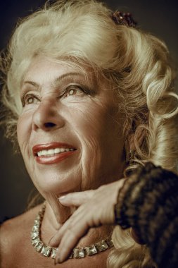 80 'li yaşlarda güzel bir kadının portresi. Akşam makyajı, saç stili ve zarif mücevherleri var. Yaşlandım. Güzellik ve yaşlılık. Stüdyo resmi.
