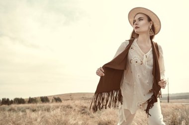 Romantik boho ve hippi tarzı. Boho tarzı kıyafetler ve aksesuarlar içinde güzel bir kız bozkırda özgürlüğün tadını çıkarıyor. Yaz modası. Boşluğu kopyala.