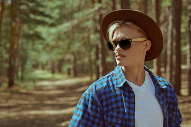 Turizm, doğa keşfi. Çam ormanında yolda duran yakışıklı bir yürüyüşçünün portresi. Aktif dinlenme, yürüyüş, macera.