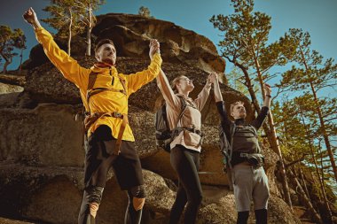 Aktif sağlıklı yaşam tarzı. Sırtlarında sırt çantalarıyla bir grup genç turist, dağlarda el ele tutuşup dağın zirvesine çıkmaktan mutluluk duyuyorlar..