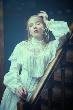 Beyaz dantel elbiseli güzel bir bayan klasik klasik bir apartman dairesinde, açık bir sis bulutuyla çevrili merdivenlerde duruyor. Viktorya tarzı. Tarihi roman..