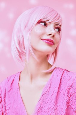 Pembe kız tarzı. Pembe saçlı, pembe makyajlı ve parlak çilli güzel bir genç kızın portresi. Asya anime tarzı. Pembe arkaplan.