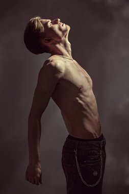 Siyah ışıkta gözleri kapalı, çıplak bedeniyle düşünceleri tarafından işkence edilen yakışıklı ve etkileyici genç bir adamın portresi. Duygular, iç dünya, psikoloji. 