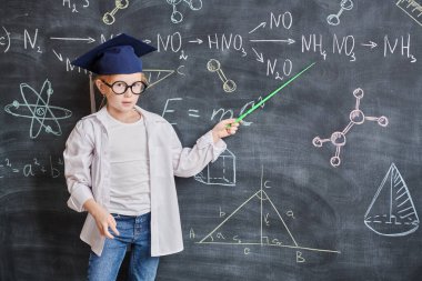 Beyaz gömlekli ve gözlüklü akıllı bir kız elinde bir işaretçiyle temel formülleri açıklıyor. Eğitim. Akıllı çocuklar.. 