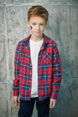 Yakışıklı bir çocuğun portresi şık günlük kıyafetlerle şık bir saç stili ile grunge arka planda poz veriyor. Çocuk modası.