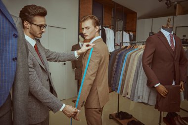 Zengin genç adam, kaliteli erkek giyim mağazasında terzilik hizmeti alıyor. Erkeklerin iş modası. 