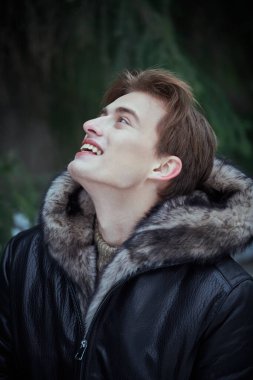 Parkta güzel bir kış gününün tadını çıkaran siyah deri ceketli neşeli sarışın bir adamın portresi. Erkek modası. Mutlu kış günleri..